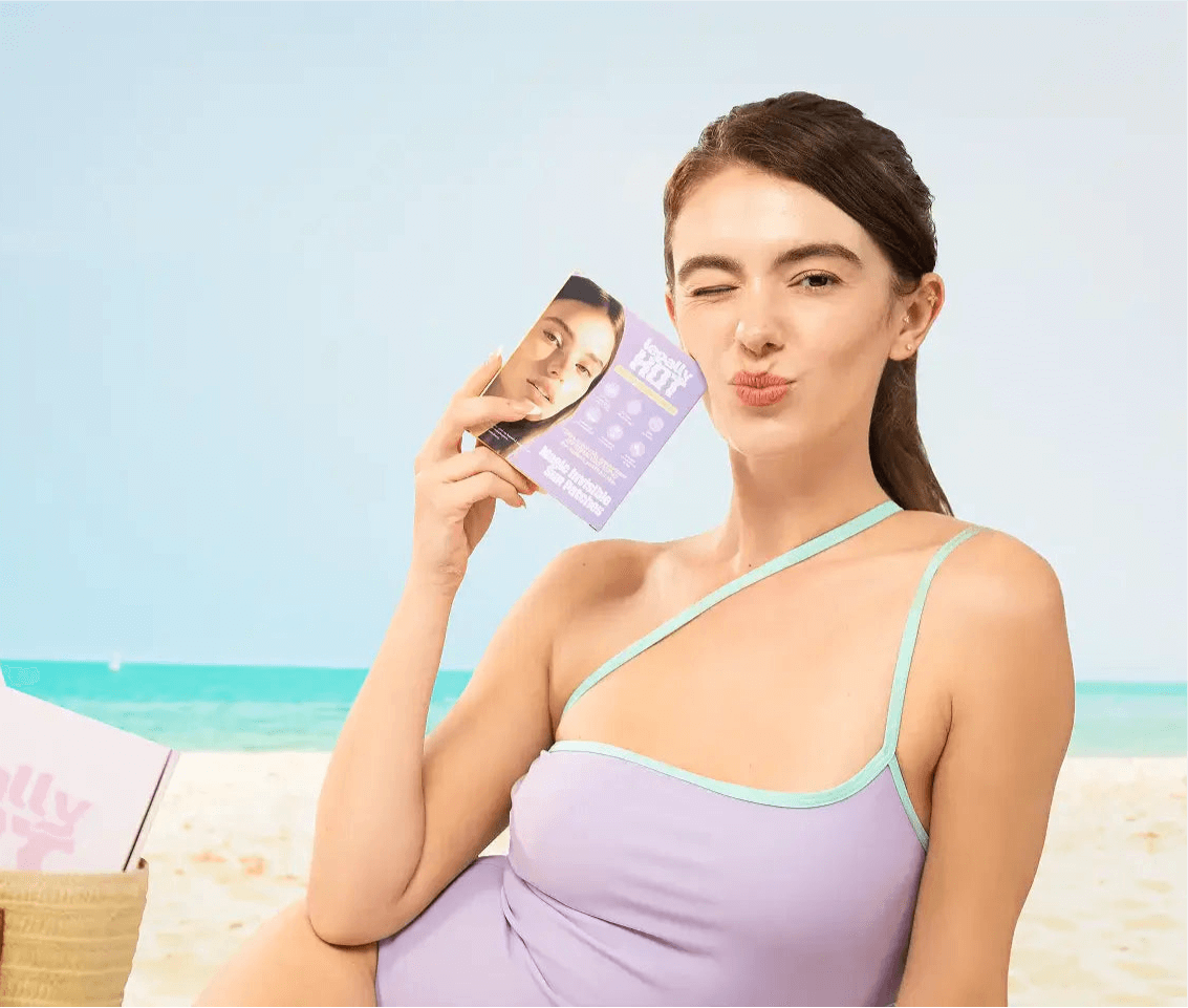 Woman holding 12-Hour Invisible UPF 50+ Sun Patches at the beach, smiling and enjoying sun protection.