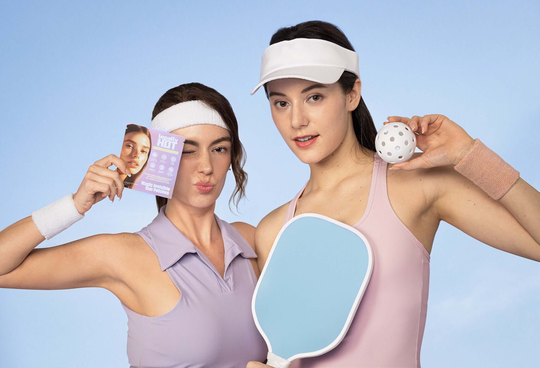 Two women showing 12-Hour Invisible UPF 50+ Sun Patches with pickleball equipment against a blue background.